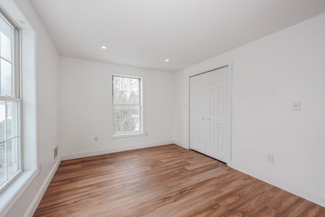 unfurnished bedroom featuring recessed lighting, a closet, baseboards, and wood finished floors