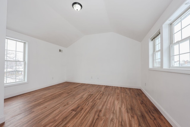 interior space with dark wood finished floors, visible vents, vaulted ceiling, and baseboards