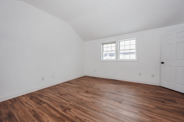 spare room with dark wood-type flooring, lofted ceiling, and baseboards