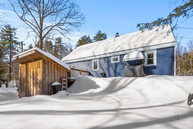 snow covered rear of property featuring a chimney