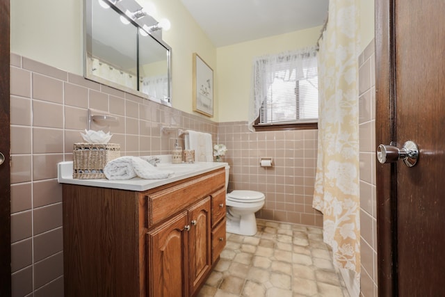 full bathroom featuring toilet, wainscoting, tile walls, and vanity