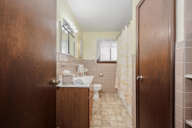 full bath featuring a wainscoted wall, tile walls, curtained shower, toilet, and vanity