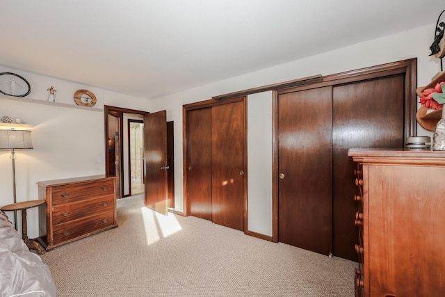 unfurnished bedroom with multiple closets and light colored carpet