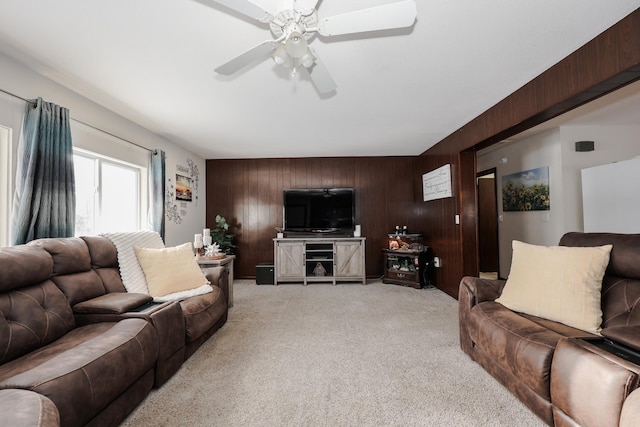 living room with ceiling fan, wooden walls, and light colored carpet