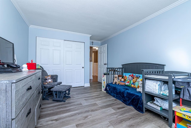 bedroom featuring a textured ceiling, a closet, wood finished floors, and crown molding