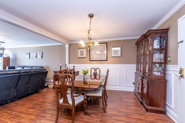 dining area with ornate columns, dark wood-type flooring, ornamental molding, and a decorative wall