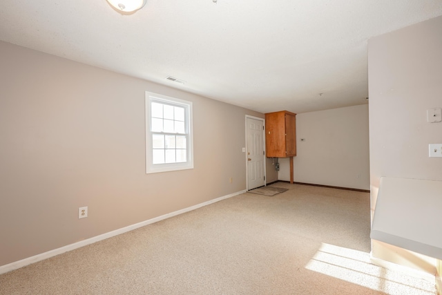 spare room featuring light carpet, visible vents, and baseboards