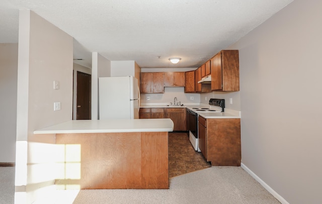 kitchen with white appliances, brown cabinetry, a peninsula, light countertops, and under cabinet range hood