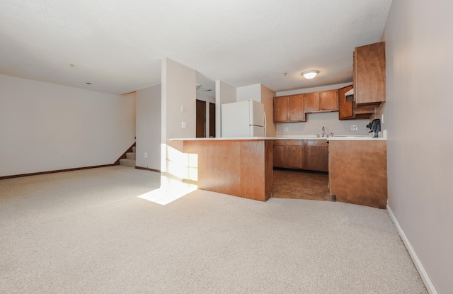 kitchen with light carpet, open floor plan, brown cabinets, freestanding refrigerator, and light countertops