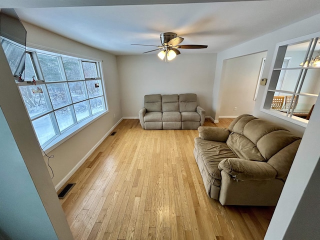 living room featuring light wood finished floors, a ceiling fan, and baseboards