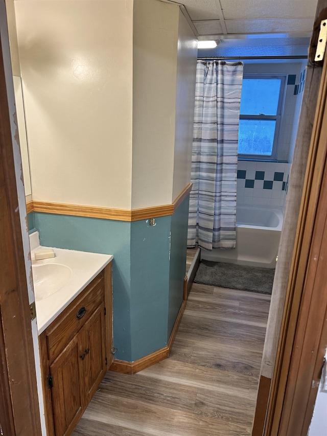 bathroom featuring shower / bath combo with shower curtain, vanity, baseboards, and wood finished floors