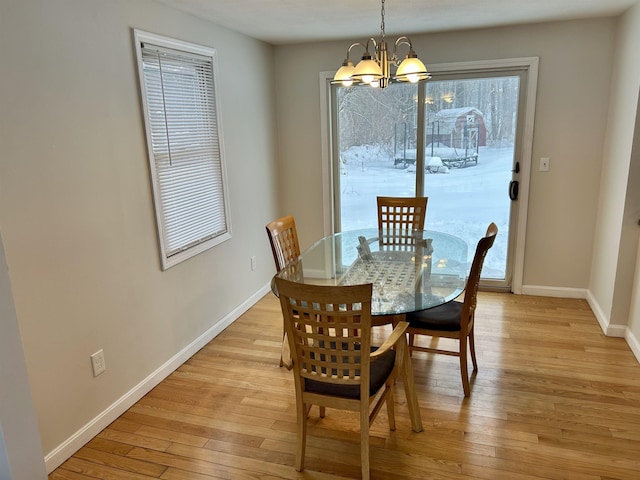 dining room featuring a chandelier, light wood-type flooring, and baseboards