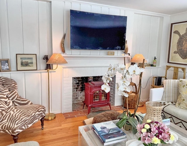 living area with ornamental molding, a wood stove, a decorative wall, and light wood finished floors