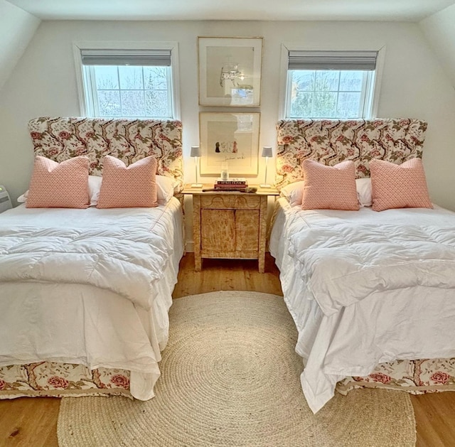 bedroom with multiple windows, vaulted ceiling, and wood finished floors