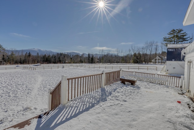 snowy yard with a rural view and a mountain view