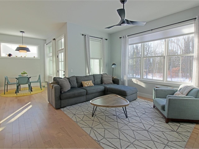 living room featuring light wood-type flooring, ceiling fan, and baseboards