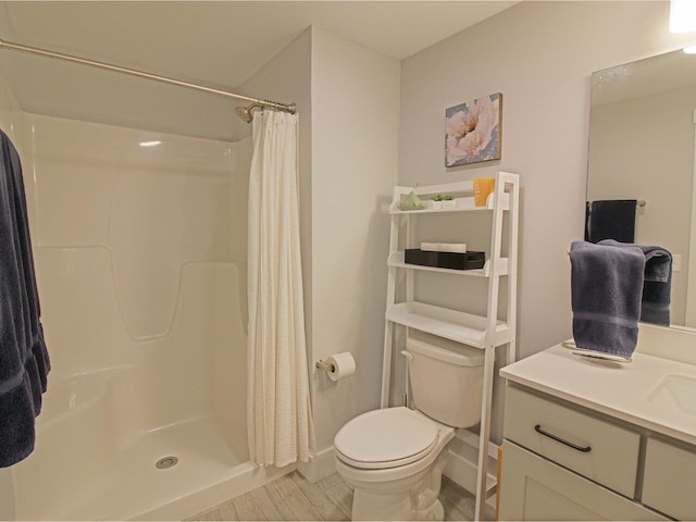 full bathroom featuring wood finished floors, a stall shower, vanity, and toilet