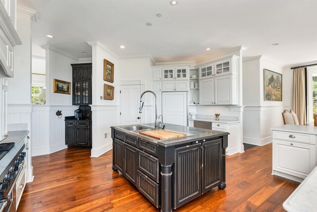 kitchen featuring light countertops, white cabinets, a sink, and an island with sink