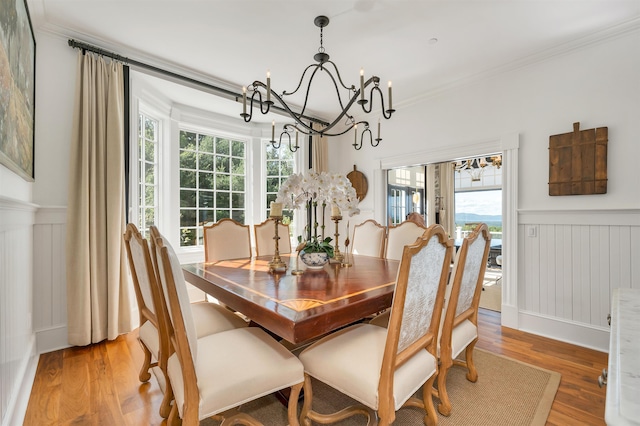 dining room featuring ornamental molding, a wainscoted wall, a notable chandelier, and wood finished floors