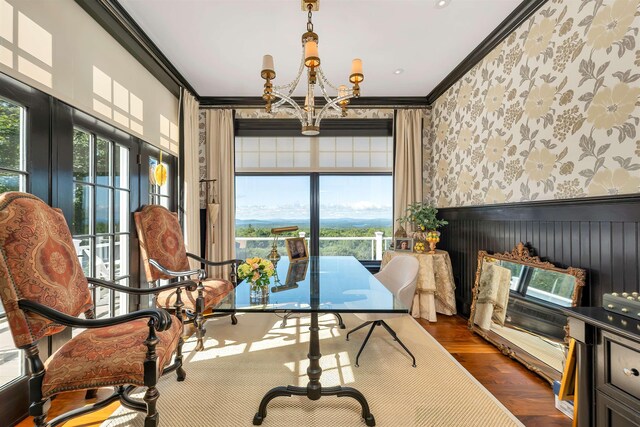 dining room with dark wood finished floors, an inviting chandelier, ornamental molding, wainscoting, and wallpapered walls