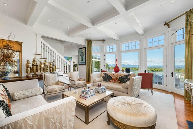 living area with coffered ceiling, light wood-style floors, ornamental molding, stairway, and beamed ceiling