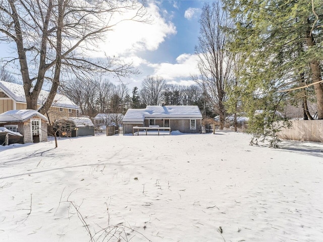 yard layered in snow featuring a storage shed, fence, and an outdoor structure