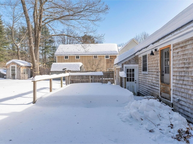 yard layered in snow with an outdoor structure, fence, and a shed