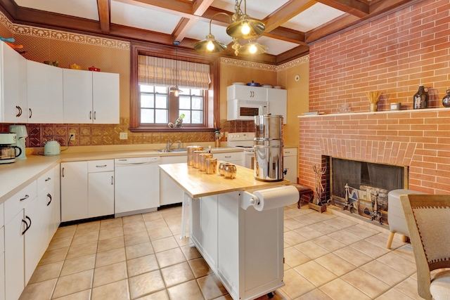 kitchen featuring white appliances, a kitchen island, white cabinets, and pendant lighting