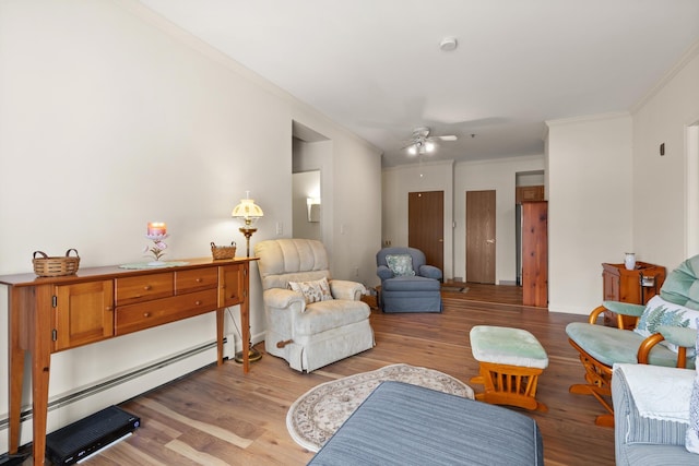 sitting room with a baseboard heating unit, a ceiling fan, light wood-style floors, and ornamental molding