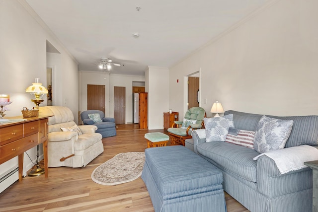 living area with light wood-style floors, crown molding, baseboard heating, and a ceiling fan