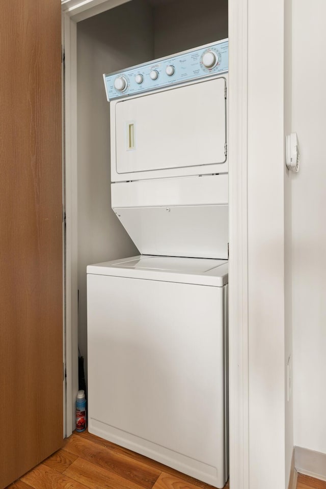 laundry area with light wood-type flooring, stacked washer and dryer, and laundry area