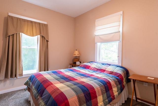 bedroom with dark colored carpet and baseboards