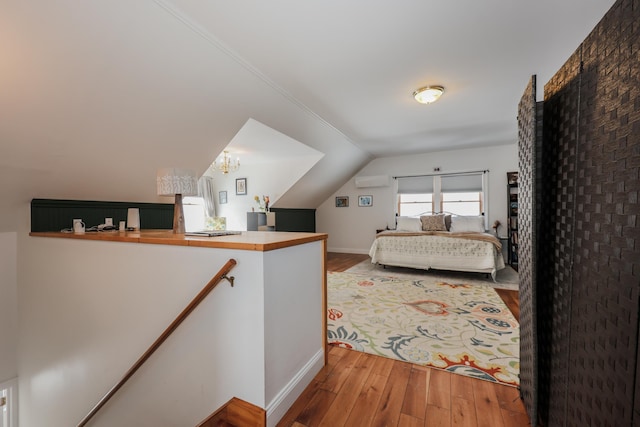 bedroom featuring light wood-type flooring, an AC wall unit, and lofted ceiling