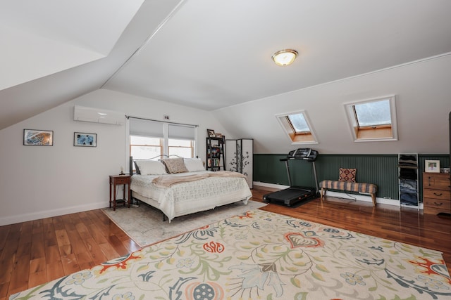 bedroom with vaulted ceiling with skylight, a wall unit AC, baseboards, and wood finished floors