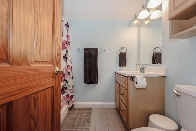 bathroom with toilet, vanity, baseboards, and tile patterned floors