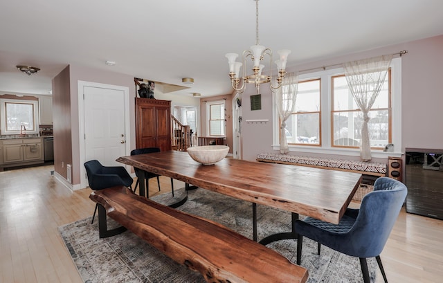 dining space featuring a chandelier, light wood-style flooring, and baseboards