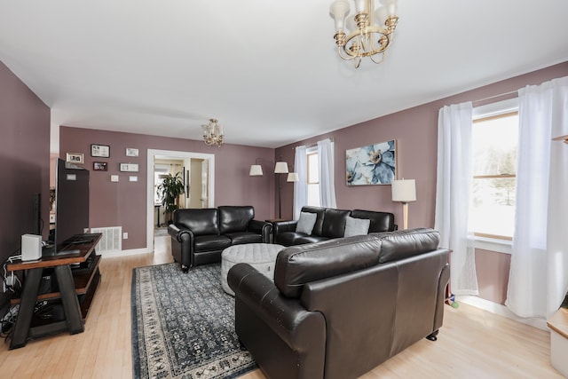 living area featuring a chandelier, a wealth of natural light, and light wood-style floors