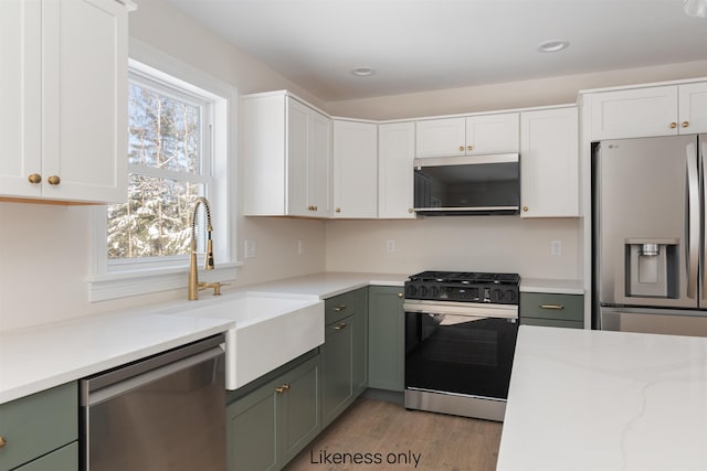 kitchen featuring green cabinets, appliances with stainless steel finishes, and white cabinetry