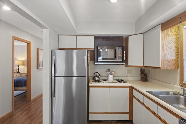 kitchen with black microwave, white gas stovetop, white cabinetry, light countertops, and freestanding refrigerator