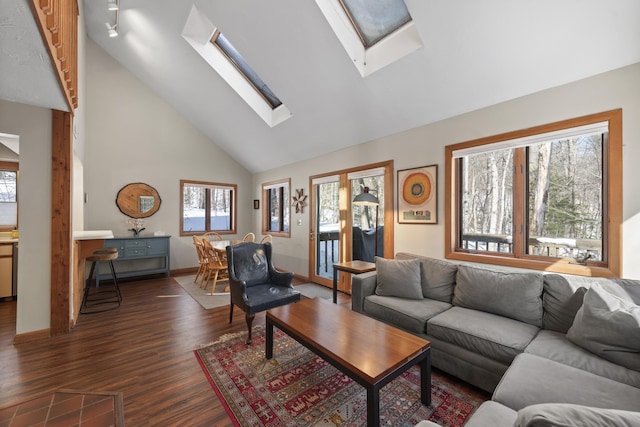 living room with high vaulted ceiling, a skylight, dark wood finished floors, and baseboards