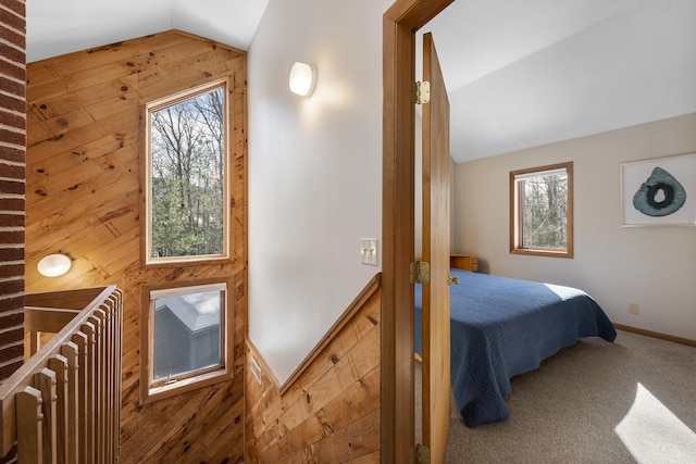 carpeted bedroom featuring lofted ceiling, wood walls, multiple windows, and baseboards