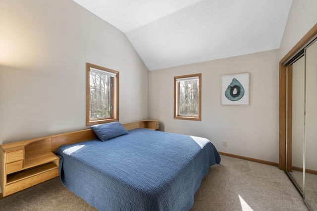 carpeted bedroom with lofted ceiling, a closet, and baseboards