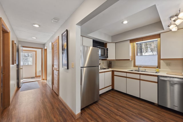 kitchen featuring a sink, white cabinetry, light countertops, appliances with stainless steel finishes, and dark wood-style floors