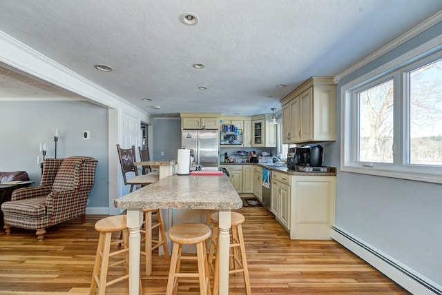 kitchen featuring stainless steel appliances, cream cabinetry, and a baseboard radiator