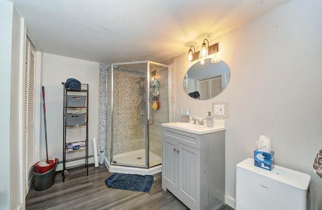 full bathroom with a stall shower, a baseboard radiator, vanity, and wood finished floors