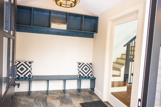 mudroom with lofted ceiling, stone finish flooring, and baseboards