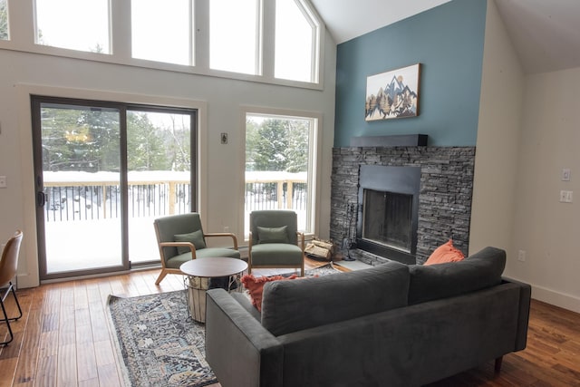 living area with high vaulted ceiling, a fireplace, wood finished floors, and baseboards