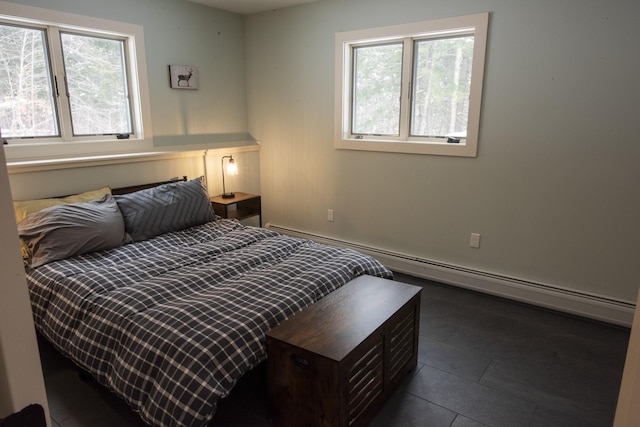 bedroom featuring dark tile patterned floors, multiple windows, and a baseboard heating unit