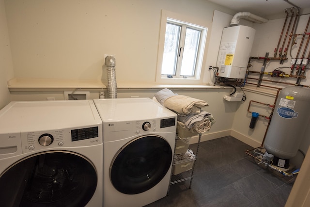 washroom featuring laundry area, water heater, baseboards, and separate washer and dryer