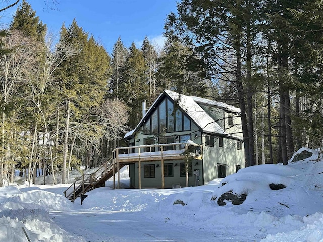 snow covered house featuring stairs and a deck